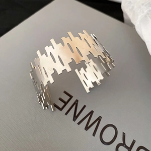 Detailed macro view of wide irregular镂空 metal cuff bracelet with a pixelated silver edge