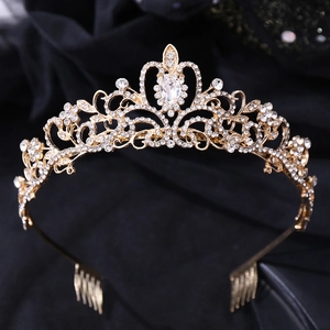Detailed view of luxury gold bridal crown with white crystals and side combs on black fabric