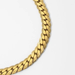 Macro shot of gold-plated cuban chain necklace with textured links and metallic finish