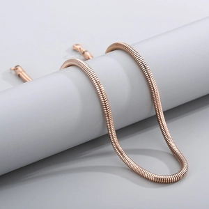 Detail of rose gold snake bone chain showing sleek texture on a minimalist display