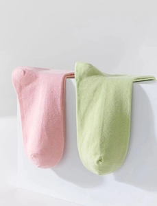 Dettaglio di calzini in cotone rosa e verde a costine su un piedistallo minimalista