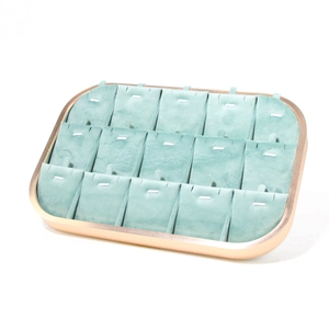 Detail of champagne gold metal jewelry tray with mint green velvet lining and 15 display slots