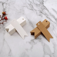 Close-up of heart-cut kraft and white paper tags with pre-punched holes on marble surface