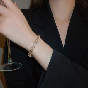 Detail of elegant gold layered crystal bracelet worn by a model holding a glass