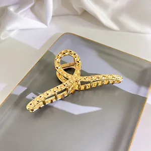 Detail einer großen goldenen Metall-Haarklammer mit Hammerschlag-Textur auf Tablett
