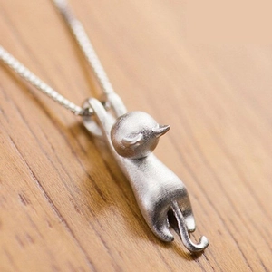 Matte silver cat pendant necklace for women on a warm wood texture background
