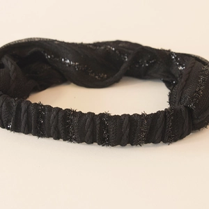 Close-up of black elastic headband with pleated texture and shimmering metallic sequins