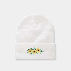 Detailed close-up of white knitted beanie featuring sunflower embroidery and soft texture