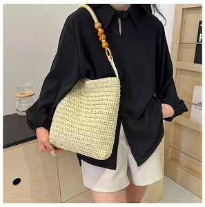 Detail of straw tote bag featuring decorative wooden bead handles and woven texture