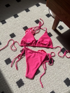 Detailed view of bright pink bikini set with 3D floral accent on a textured surface