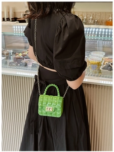 Detail of lime green quilted jelly bag with gold chain strap worn by a model