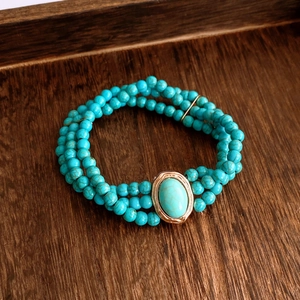 Vue macro du bracelet multicouche en perles de turquoise avec pierre ovale sertie d'or