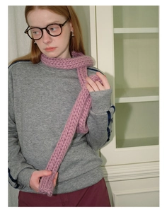 Detail showing thick chunky knit texture of pink purple scarf worn in home setting