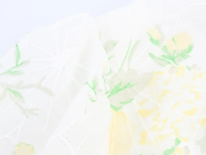 Close-up of white fabric texture with yellow floral embroidery and green leaf patterns