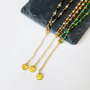 Detail of stainless steel bead necklaces with gold plating and engraved S.steel logo tag