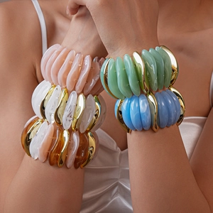 Close-up of stacked acrylic resin bracelets with marble texture and gold accents
