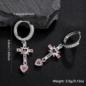Silver heart and cross drop earrings with colorful zircons on a textured black background