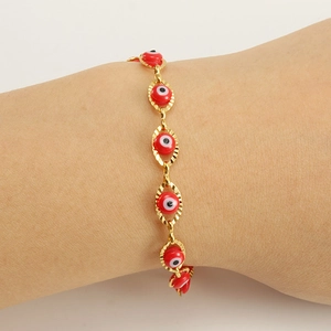 Macro detail of red enamel evil eye links and 18K gold plated stainless steel bracelet