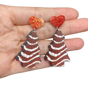 Close-up of festive Christmas tree earrings with red glitter heart studs and brown charms