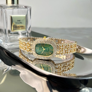 Detail of elegant gold-toned watch with green oval dial and sparkling diamond accents