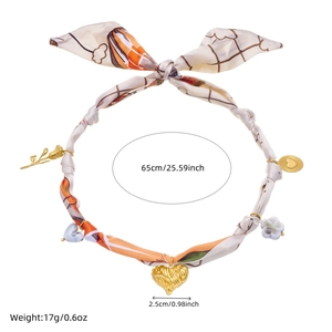 Detail of silk scarf necklace with leopard print and gold heart sun pendants