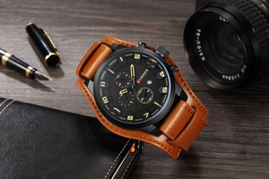 Men's leather watch with chronograph dial on a dark wooden desk with business props