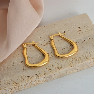 Elegant gold geometric U-shaped titanium steel earrings on a beige stone background