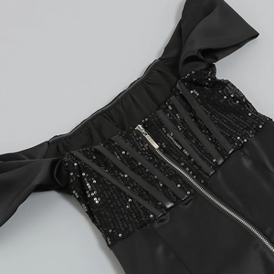 Détail de la fermeture éclair argentée sur une robe noire à paillettes et satin