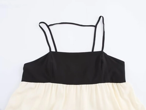 Detail of color-block camisole dress with black bodice and flowing beige chiffon skirt