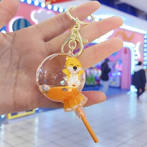 Macro detail of acrylic lollipop keychain with floating dog figure and orange liquid