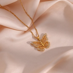 Detailed view of a gold hollow butterfly pendant necklace with white zircons on pink silk