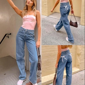 Close-up of white decorative bows on the back pockets of high-waist wide-leg blue jeans