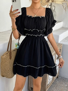 Detail of black mini dress with white ruffled edges, puff sleeves and a cinched waistline