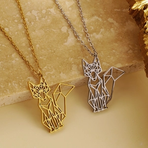 Macro shot of silver and gold geometric origami fox necklaces on marble stone