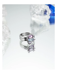 Detail of a minimalist double-band silver ring featuring square purple and blue zircons