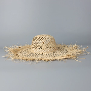 Close-up of hollow woven straw hat featuring wide brim and natural fringe edges