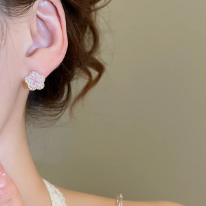 Close-up of pink flower stud earrings with zircon stones worn by a model