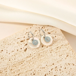 Titanium steel mother of pearl flower drop earrings on a natural stone surface