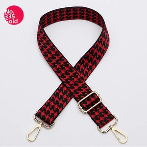 Detail of red and black houndstooth woven bag strap with golden metal lobster clasps