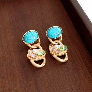 Detail eines Vintage-Goldohrrings mit Türkis, kleiner Perle und grünem Kristallanhänger