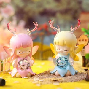Close-up of cute resin deer fairy figurines with glowing crystal balls in a forest scene