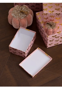 Detail of pink Christmas gift box set with gold bow prints on dark wood floor