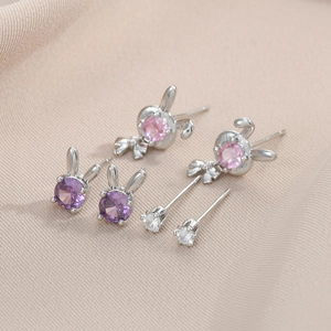 Détail de l'ensemble boucles d'oreilles lapin avec zircons violets et roses sur satin
