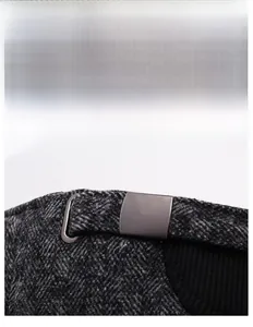 Detail of winter baseball cap showing adjustable metal buckle and grey herringbone fabric