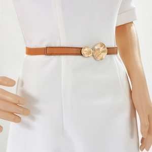 Detail of tan leather elastic belt with overlapping textured gold metal circular buckle