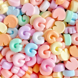 Macro shot of colorful G-shaped resin letters in pastel tones for DIY phone case crafts