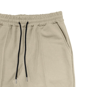 Detail of beige textured joggers featuring elastic waistband and black adjustable drawstrings