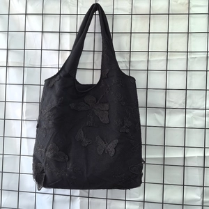 Detailed macro shot of black mesh tote bag with 3D lace butterfly embroidery decoration
