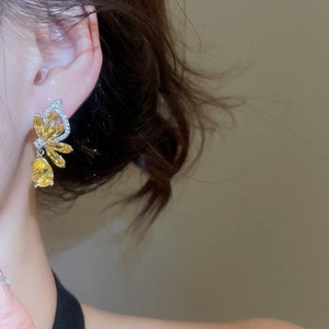 Detail view of elegant yellow zircon butterfly earrings worn by a model in warm light