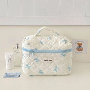 Detailed quilted cotton makeup bag featuring blue ribbon prints and a sturdy top handle